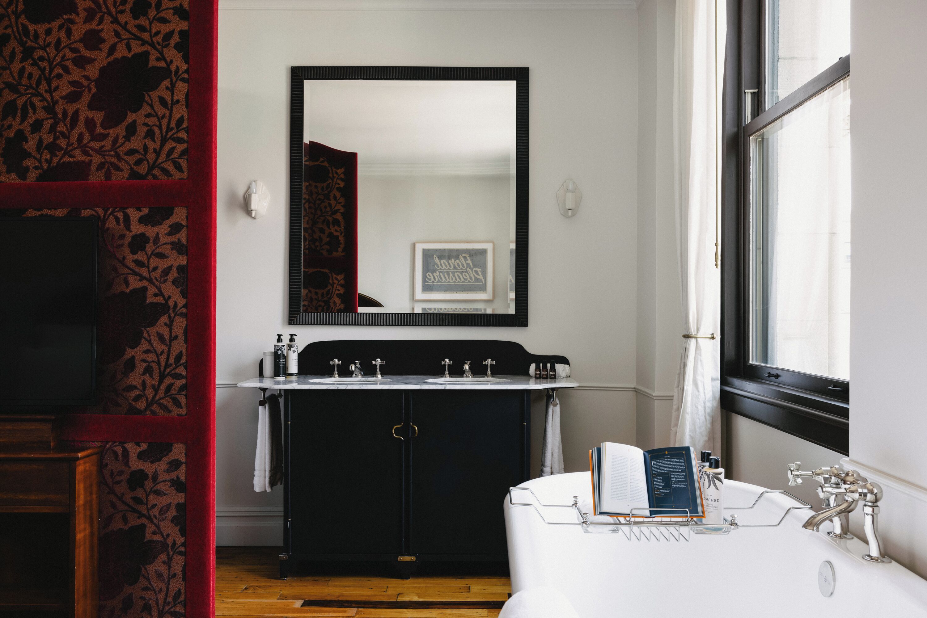 Ein Badezimmer mit einem großen Spiegel, einem Waschbecken mit mehreren Wasserhähnen, einer Badewanne und einem Fenster.