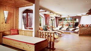 Un intérieur en bois avec un lit, des fauteuils et de grandes fenêtres.