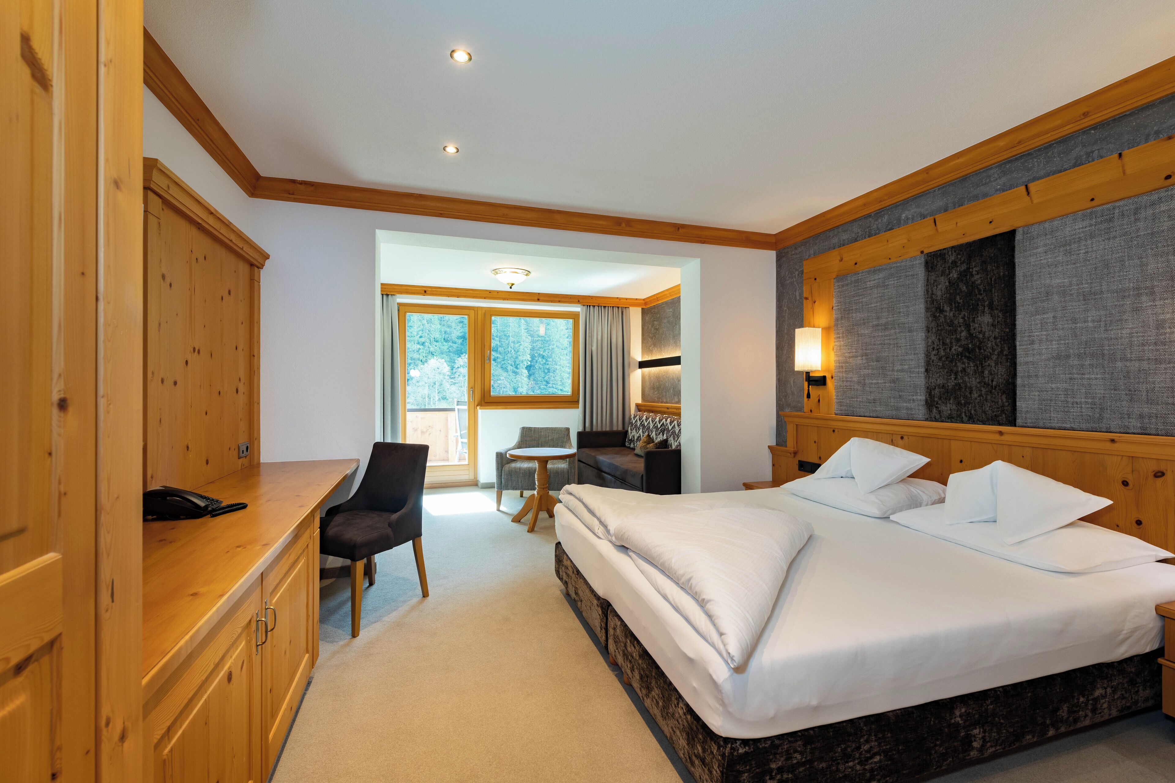 Ein Hotelzimmer mit einem großen Bett, einem Holzschrank, einem Schreibtisch und einem kleinen Tisch mit Stühlen.