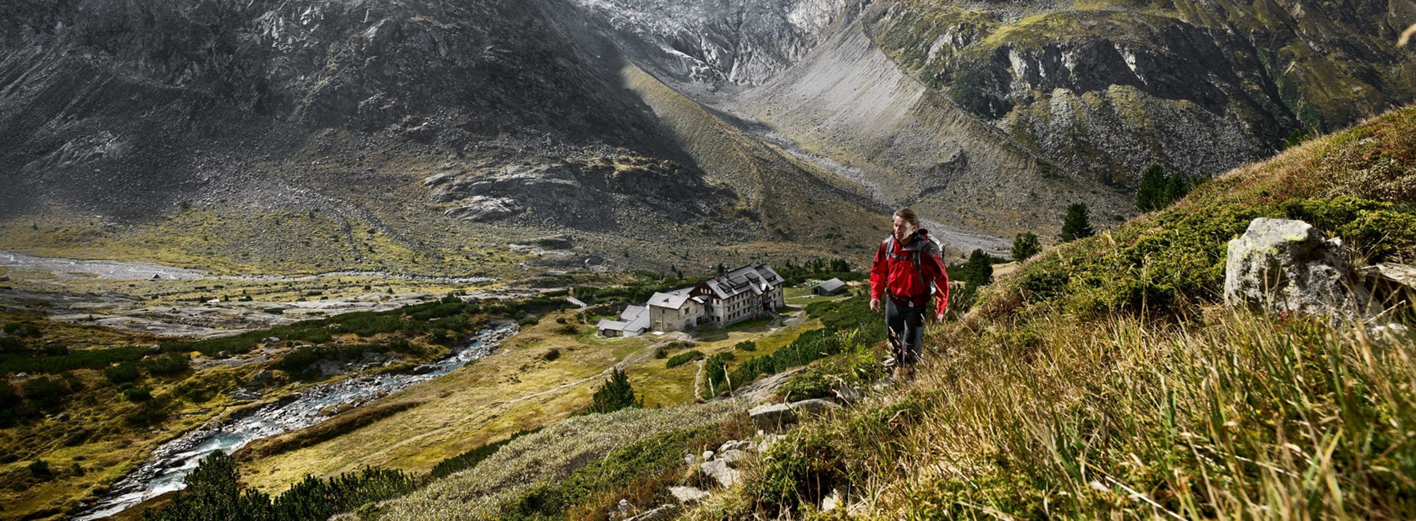 A mountainous landscape with a small lodge featuring a stone building and a river in the valley.