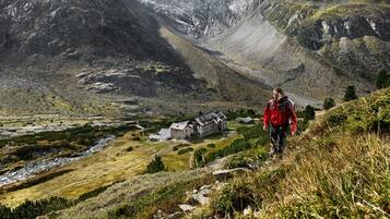 A mountainous landscape with a small lodge featuring a stone building and a river in the valley.