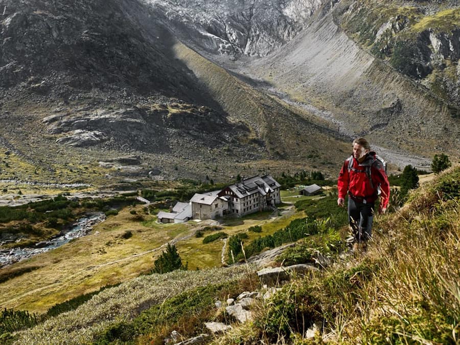 A mountainous landscape with a small lodge featuring a stone building and a river in the valley.