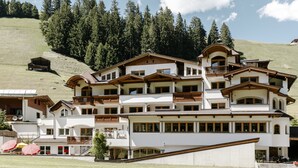 Un hôtel à plusieurs étages doté de balcons, d’un télésiège et situé dans un cadre montagneux.
