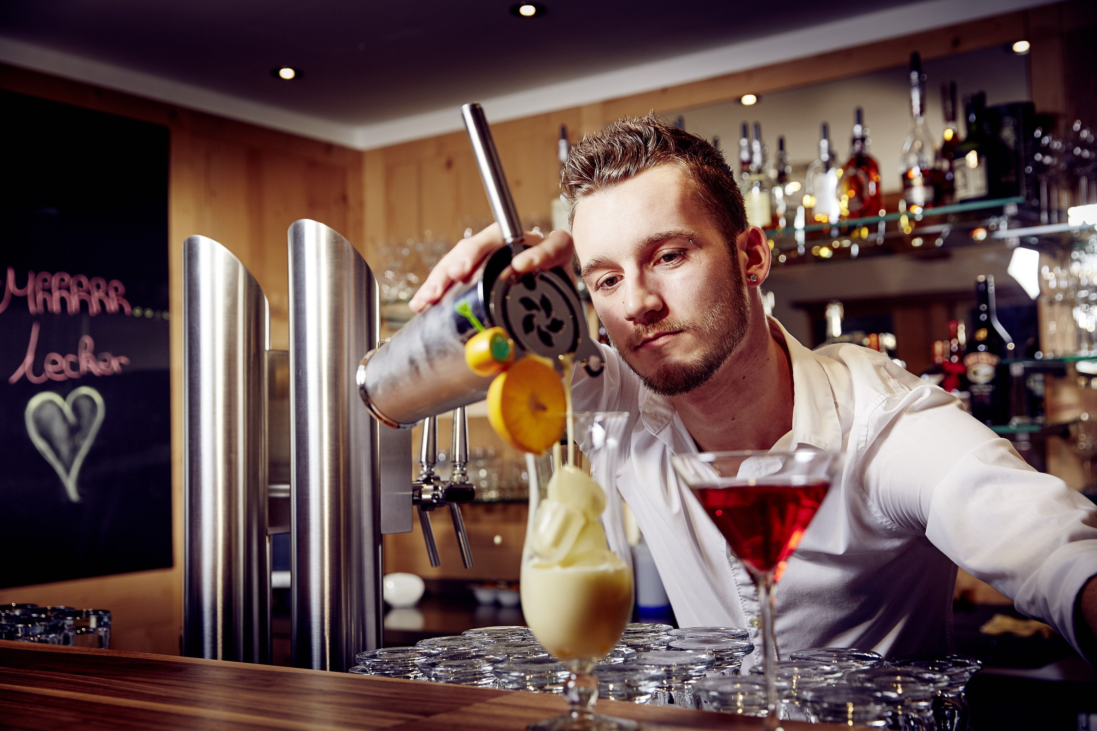 A bartender pouring a drink into a glass.