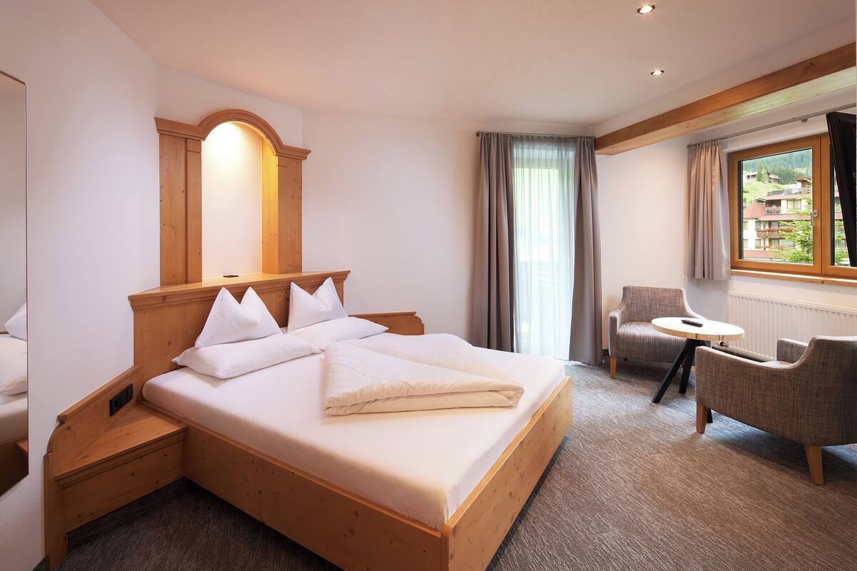 A hotel room with a wooden bed, a small round table, and a chair.