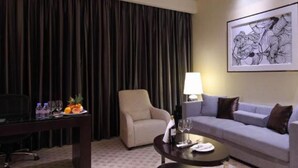Habitació d'hotel amb un sofà, una butaca, una taula de cafè i un quadre a la paret.