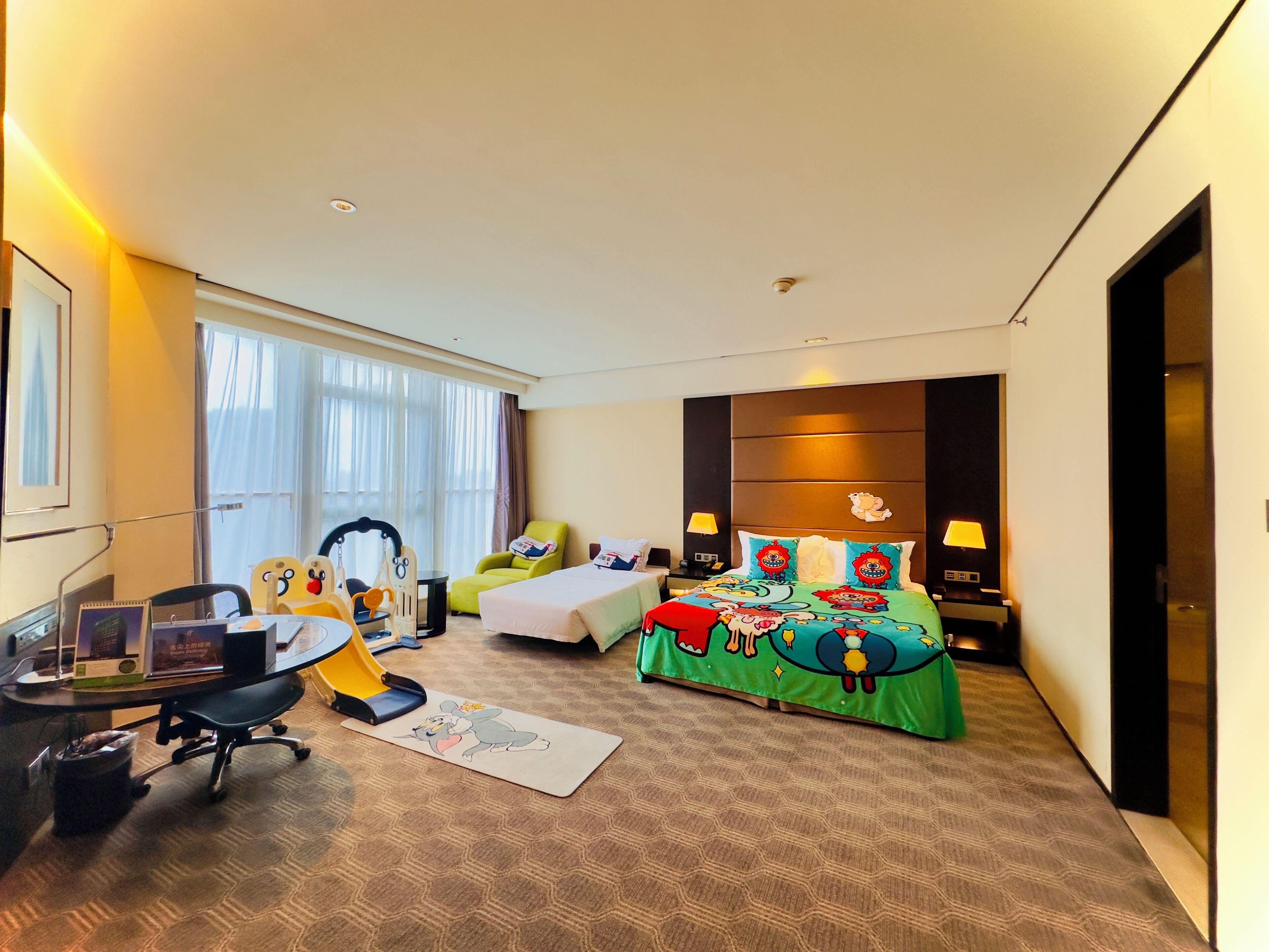 A hotel room with a bed, a desk, a chair, a small table, and a window.