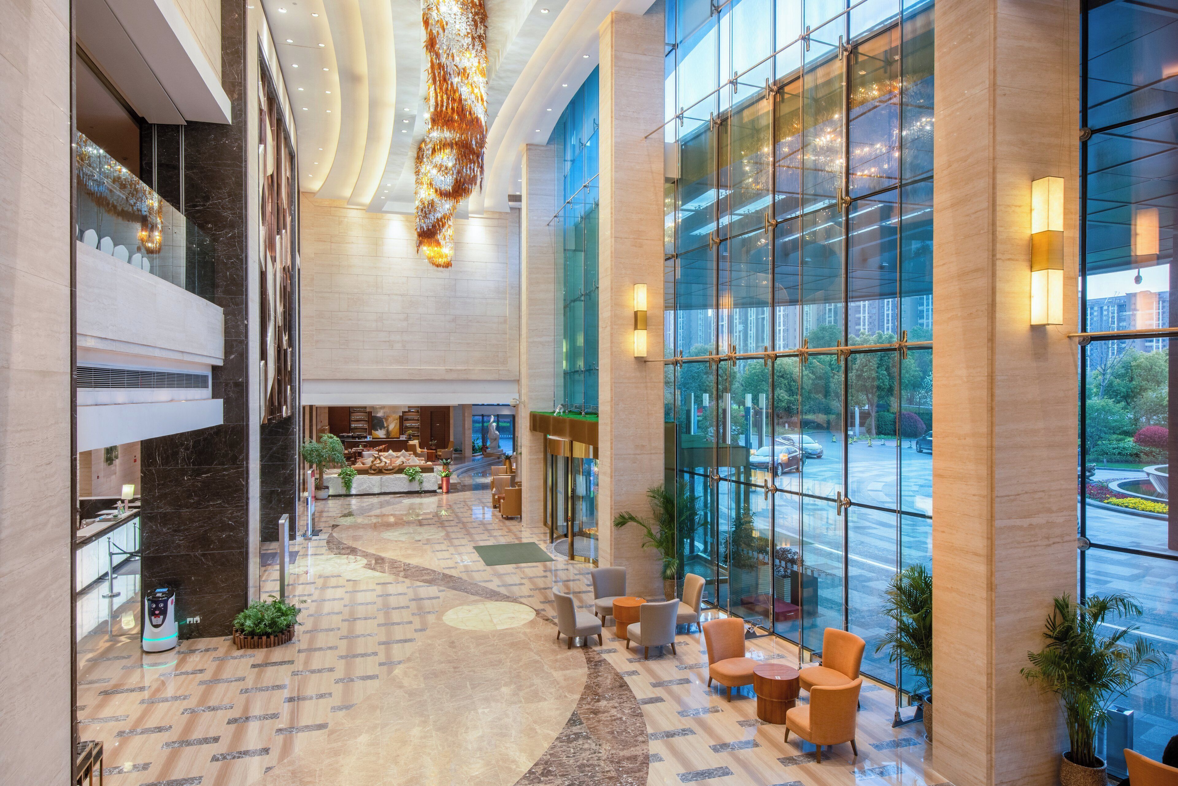A spacious lobby with a central seating area, a reception desk, and large windows offering a view of the street.