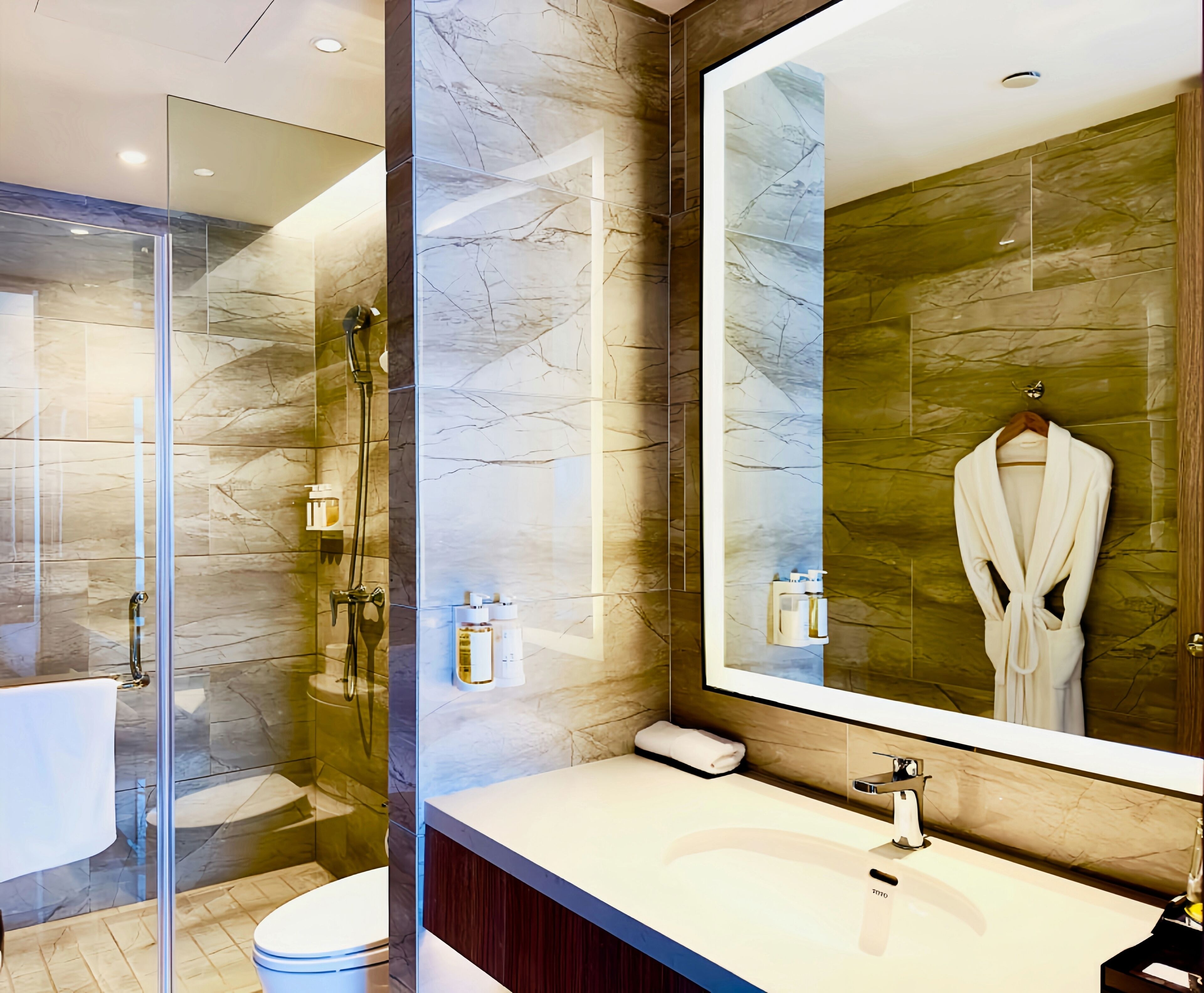 A modern bathroom with a glass shower enclosure, a large mirror, and a vanity with a sink and towel.