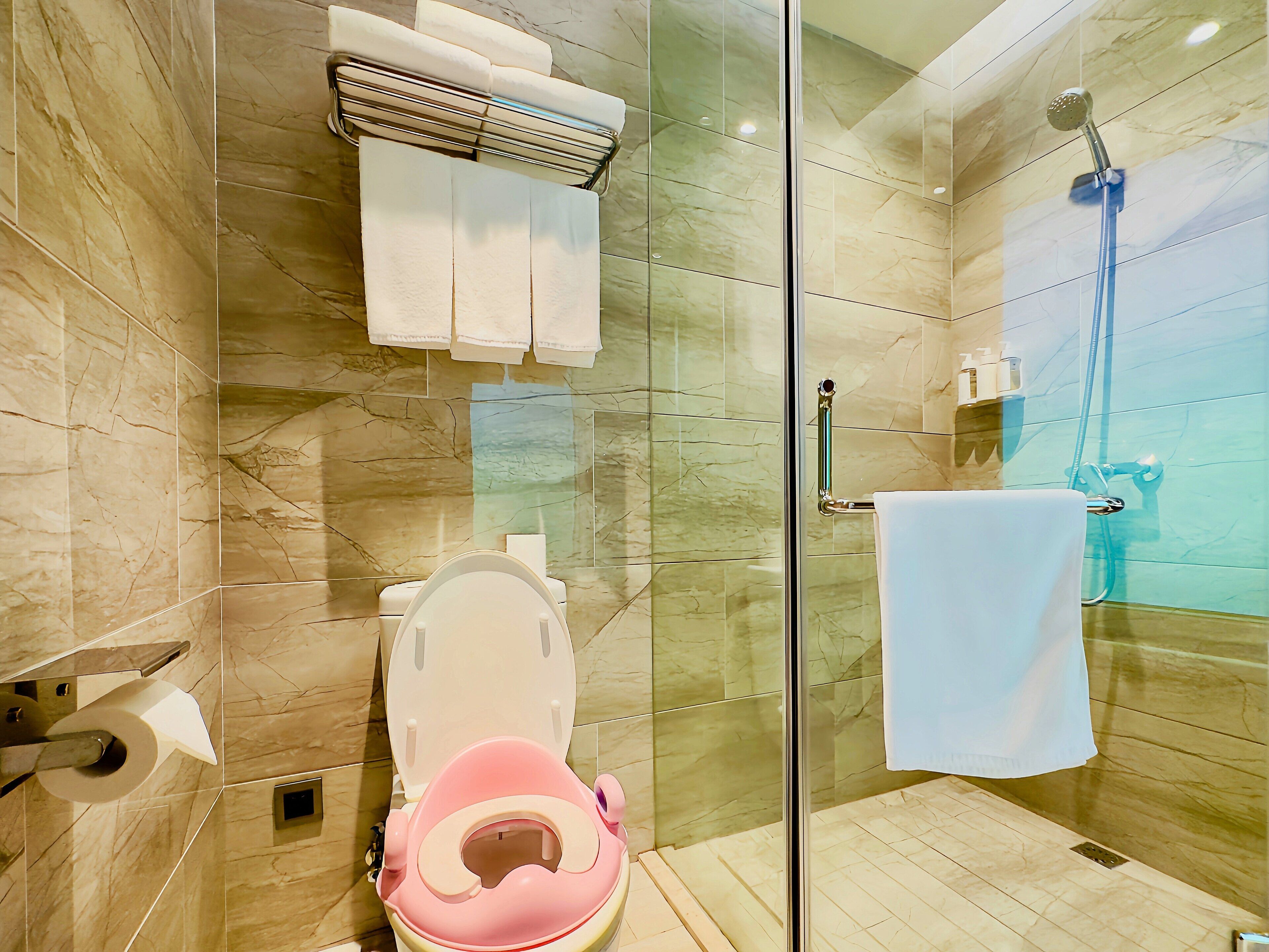 Un baño con inodoro, ducha y mampara de vidrio.