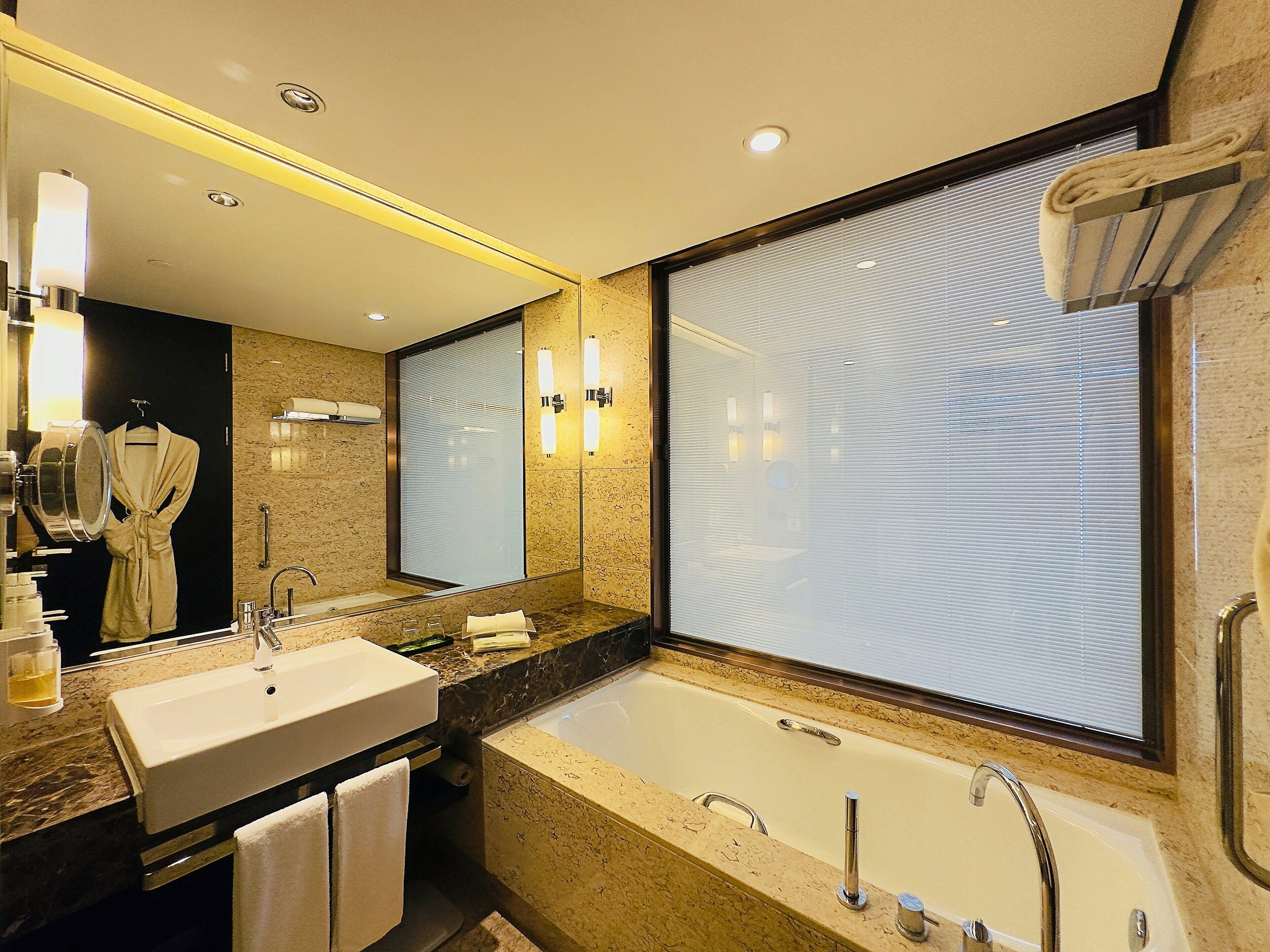 A modern bathroom with a large mirror, a sink, and a bathtub.