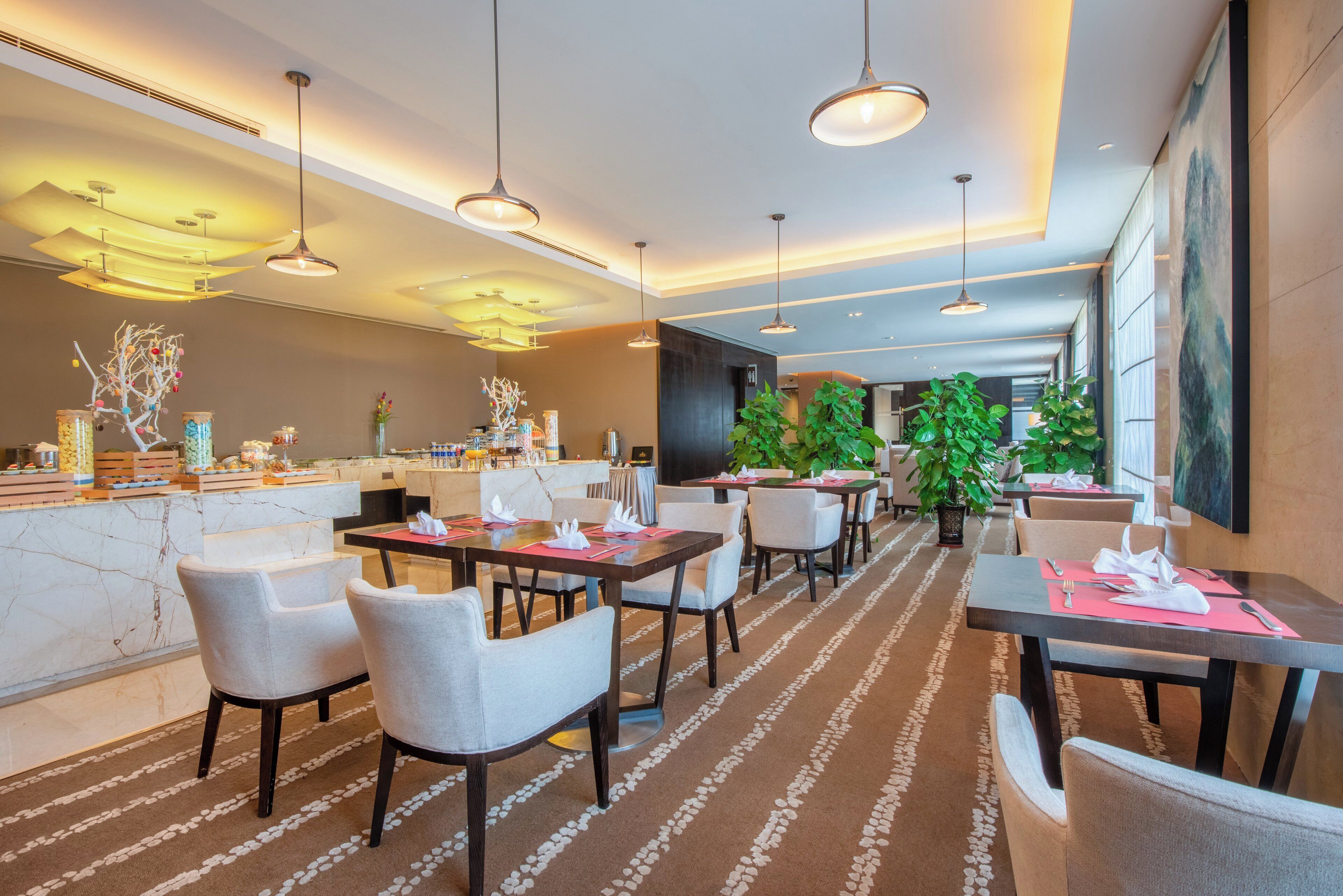 A modern hotel lobby with a marble reception desk, multiple dining tables, and chairs.