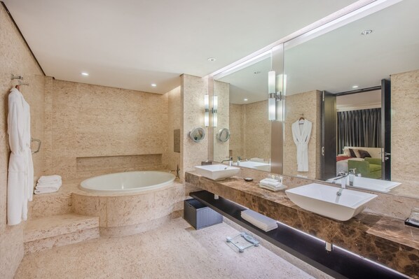 A modern bathroom with a large bathtub, two sinks, a mirror, and a towel rack.