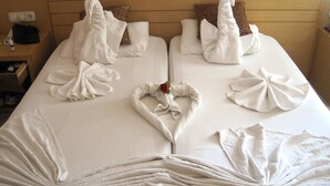 Una habitación de hotel con una cama bien hecha, dos almohadas, una mesita con una lámpara y un teléfono.