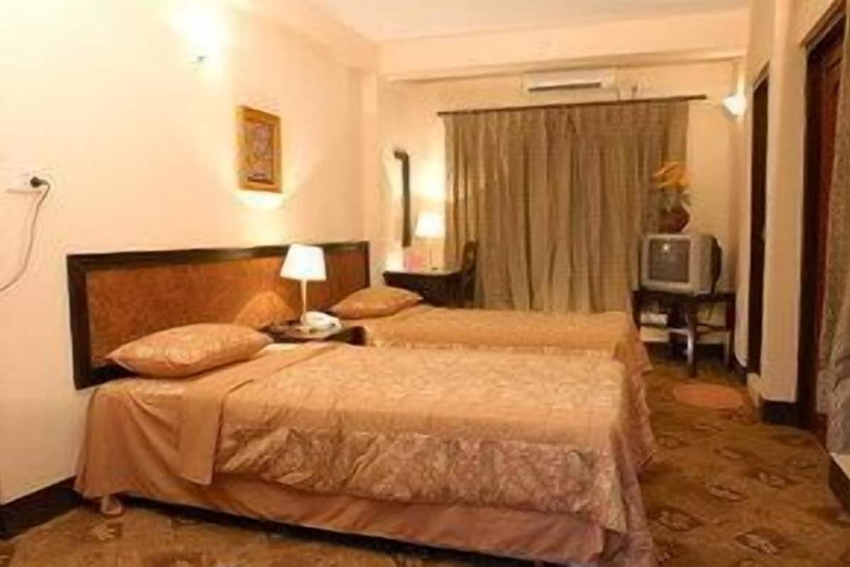 A hotel room with two beds, a television, a desk, and a chair.