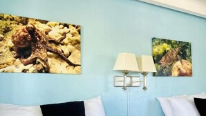 A hotel room with two beds, a blue wall, and two paintings.