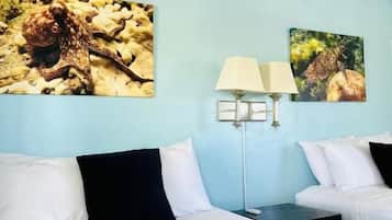 Habitación de hotel con dos camas, una pared azul y dos cuadros.
