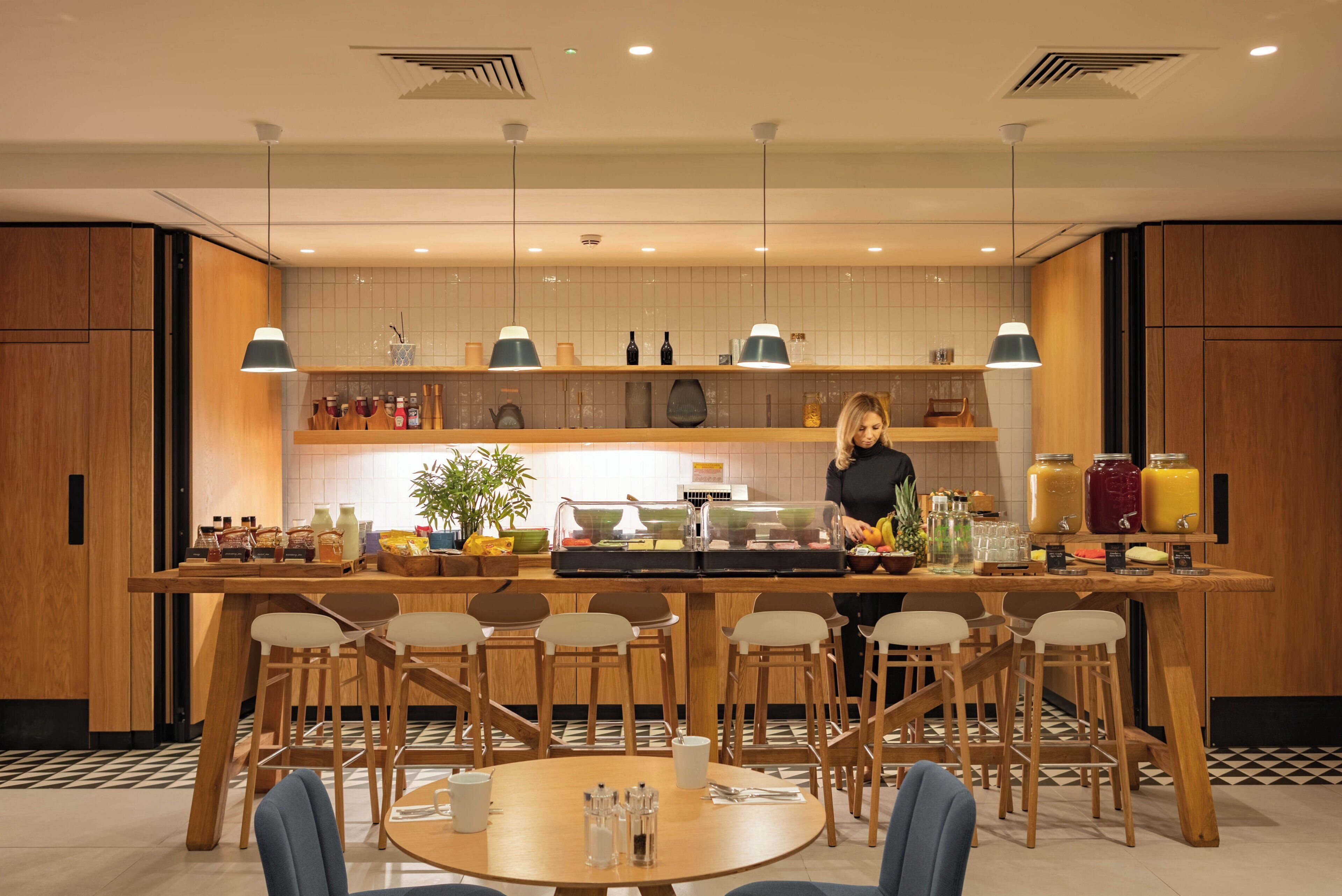 A modern kitchen with wooden cabinets, a central island with seating, and overhead pendant lighting.