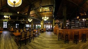 Un interior rústico con vigas de madera, candelabros y una zona de bar.