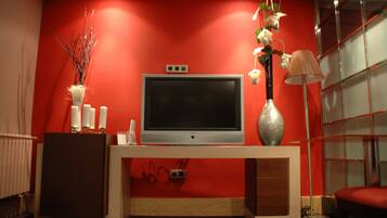 A modern living room with a flat-screen TV, a decorative vase, and a lamp on a wooden console table.