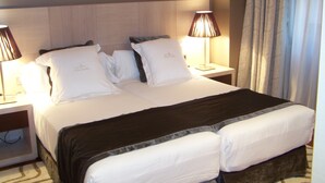 Una habitación de hotel con una cama grande, dos lámparas de noche y un cabecero.