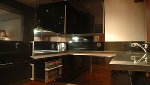 Una cocina moderna con armarios negros, electrodomésticos de acero inoxidable y piso de madera.