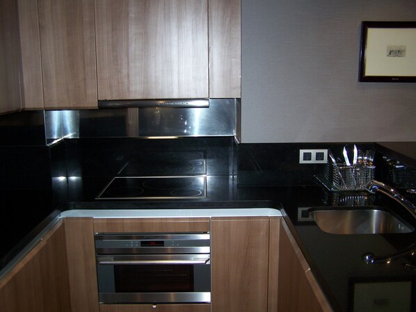 A modern kitchen with stainless steel appliances, wooden cabinets, and a built-in oven. - Washington Parquesol Suites & Hotel (Valladolid)