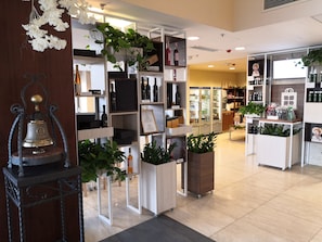 A modern retail space with shelves displaying various products, a refrigerated display case, and decorative plants.