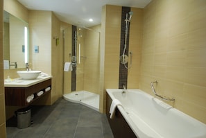 A modern bathroom with a bathtub, shower, and sink.
