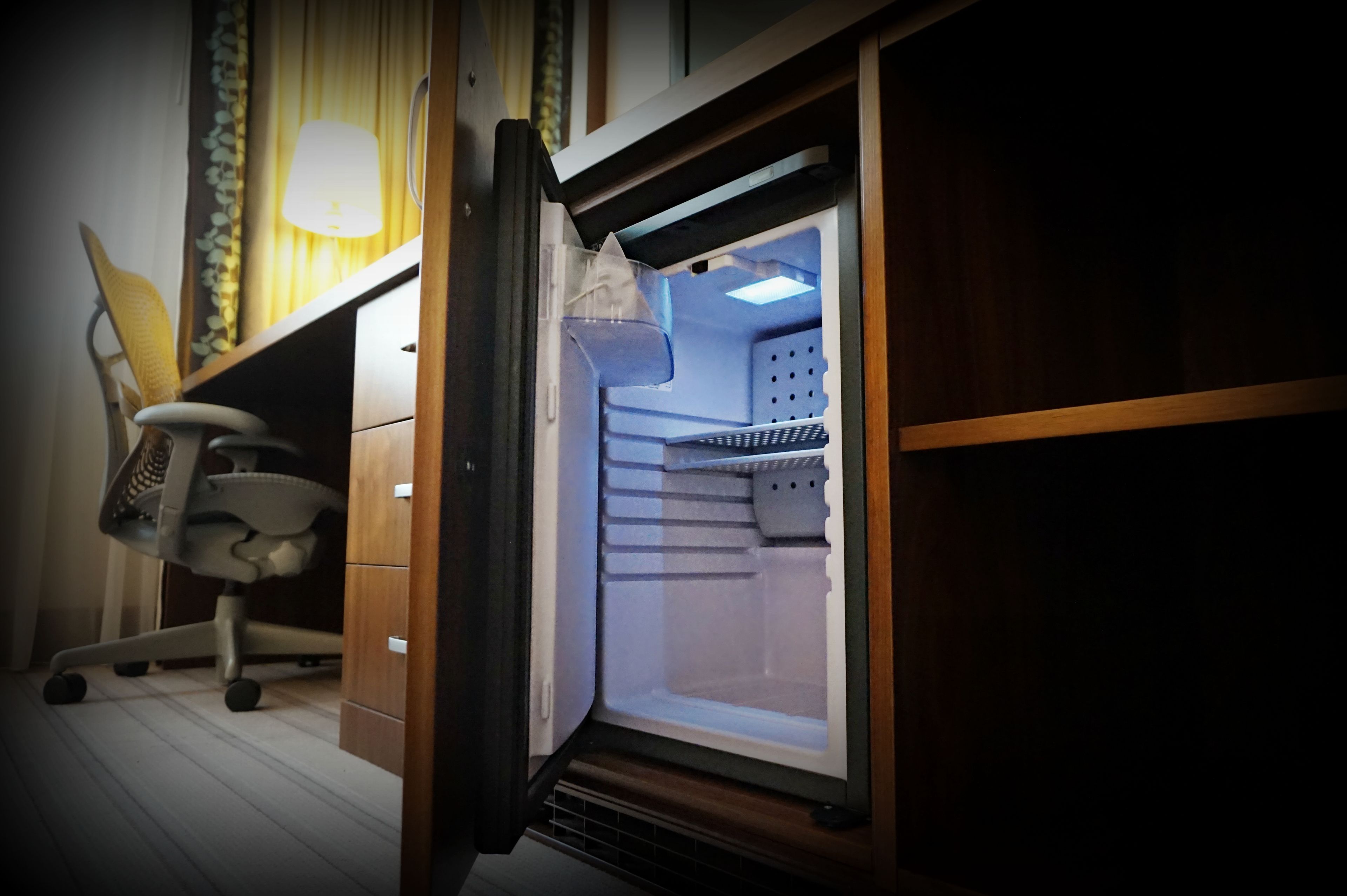 A compact office space with a desk, chair, and a refrigerator.