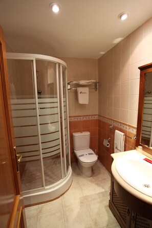 Un baño con cabina de ducha de vidrio, inodoro y lavabo con espejo.