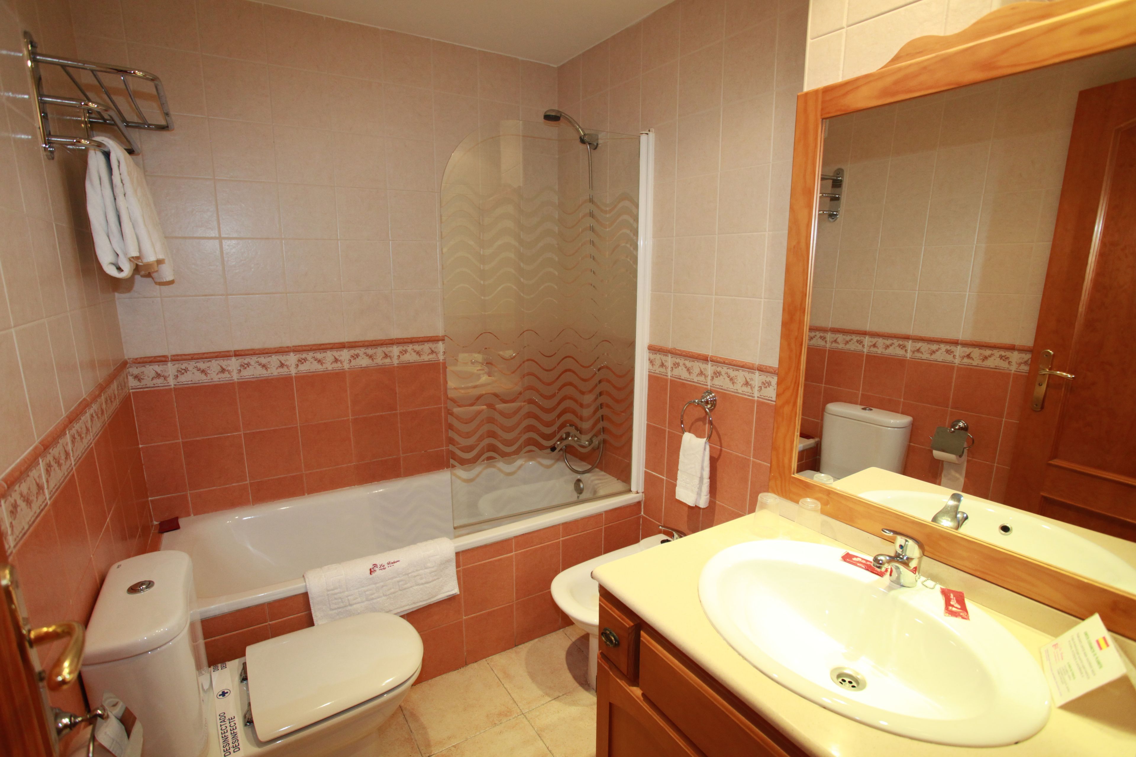 Un baño con bañera, inodoro, lavabo y ducha con puerta de vidrio.