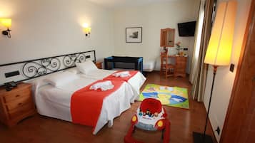 Ein Hotelzimmer mit Bett, Nachttisch, Lampe und einer Kinderspielecke mit einem Spielzeug-Krankenwagen.