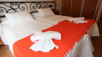 Una cama doble con ropa de cama blanca y una manta roja.