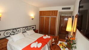 A hotel room with a bed, a wooden wardrobe, a desk with a fruit bowl, and a mirror. - La Bodega Hotel (Ciudad Rodrigo)