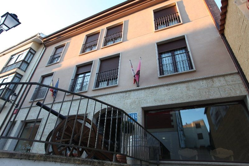 A multi-story building with a balcony, a large wheel, and a flag.