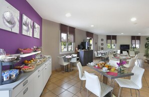 A modern dining area with white chairs, a buffet counter with food and drinks, and a bar area. - Vacancéole - Resid'price (Merville)