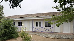 A building with a tiled roof, white exterior walls, and a gravel driveway.