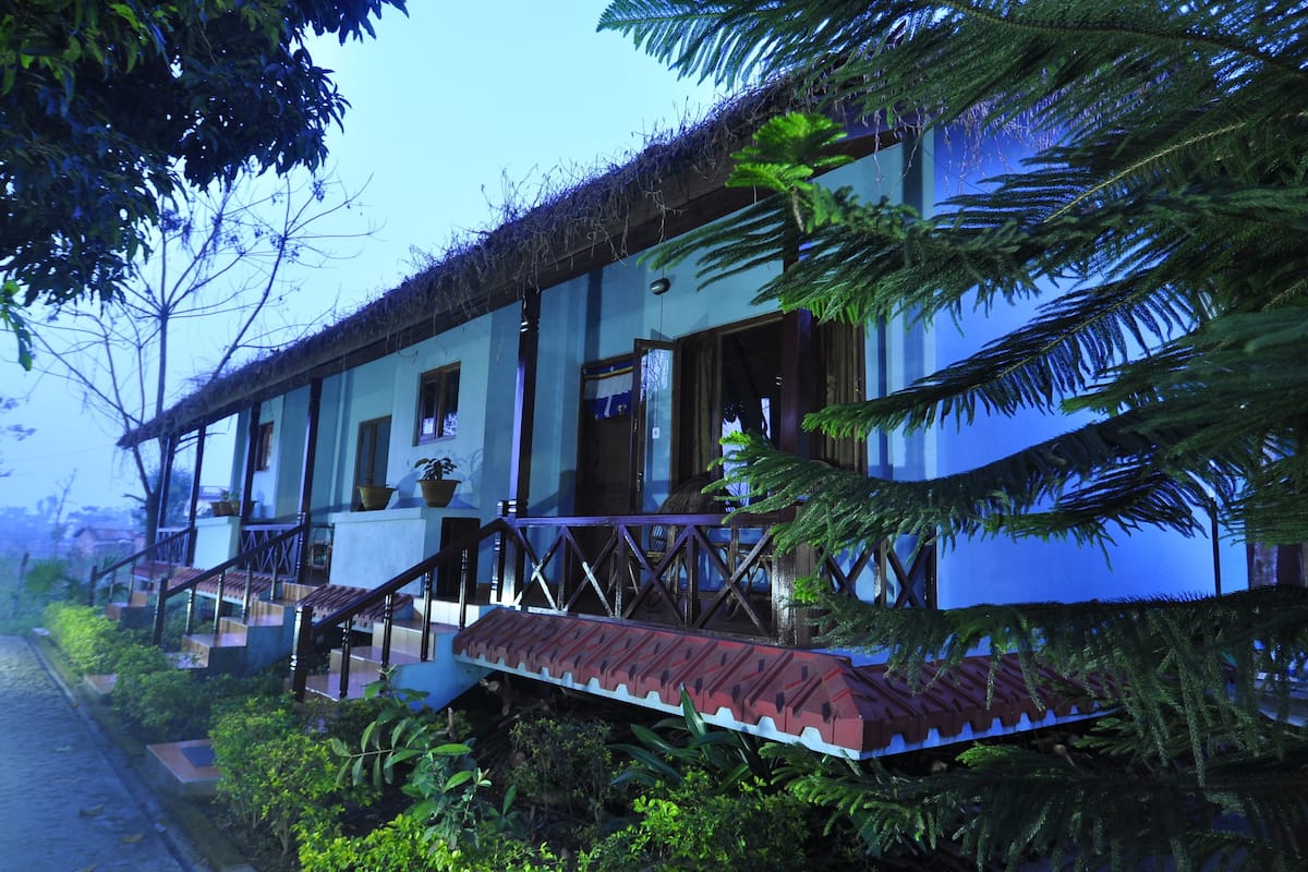 A traditional house with a thatched roof, wooden staircase, and a balcony.