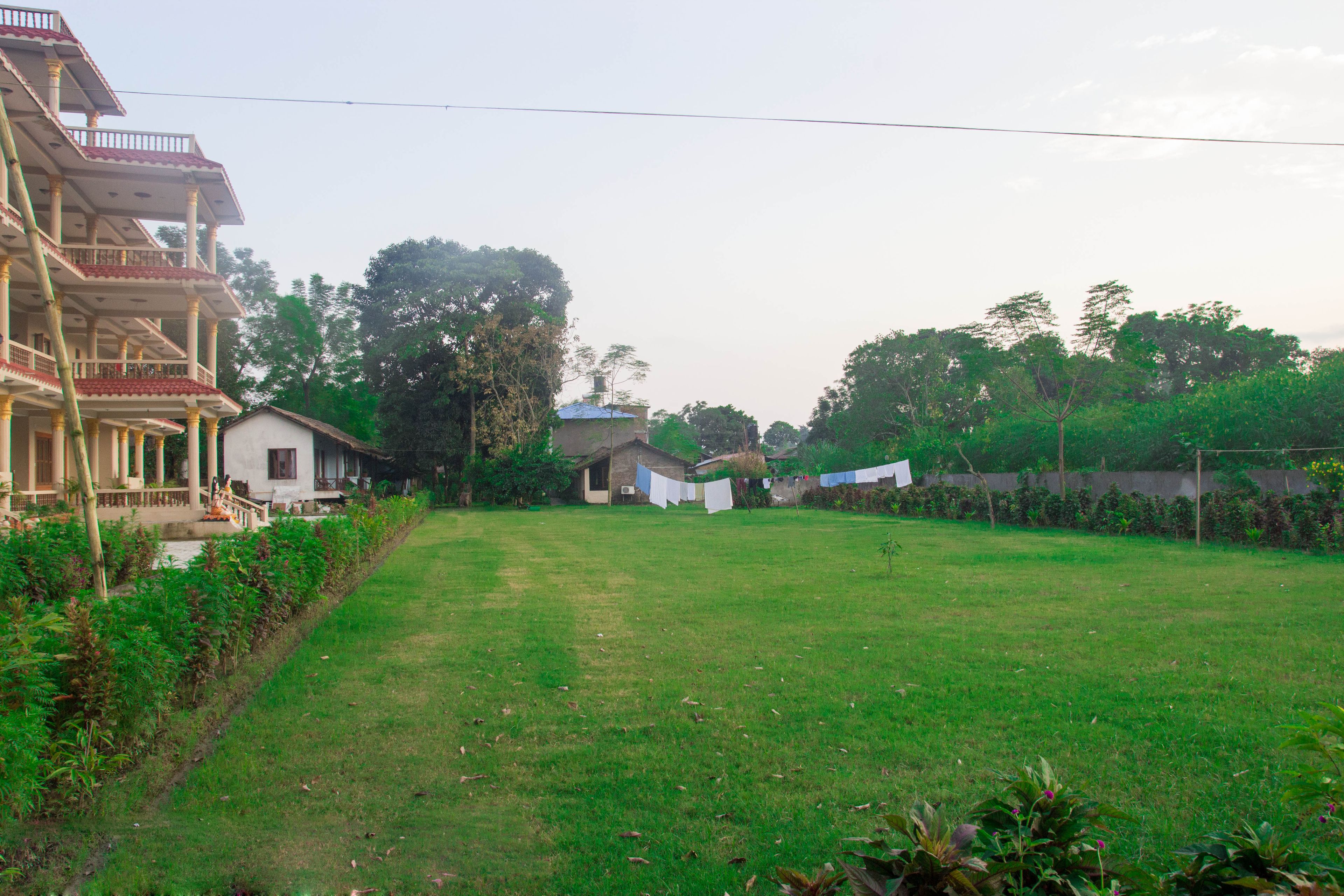 A residential area with a large house featuring a balcony and a smaller house in the background.