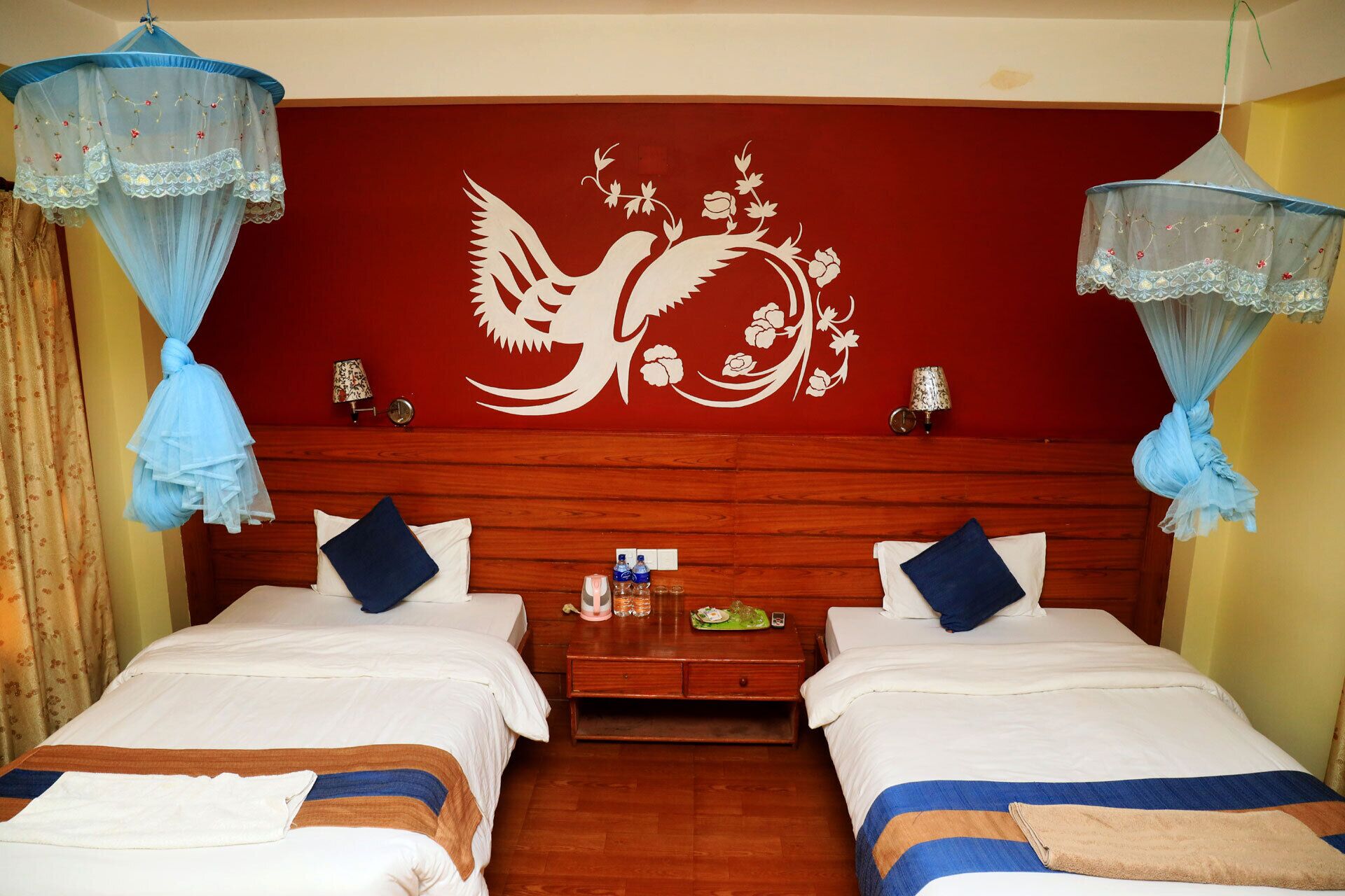 Quarto de hotel com duas camas, cabeceira de madeira e um mural decorativo na parede.