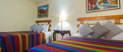 A hotel room with two beds, a nightstand, a lamp, and two paintings on the walls.
