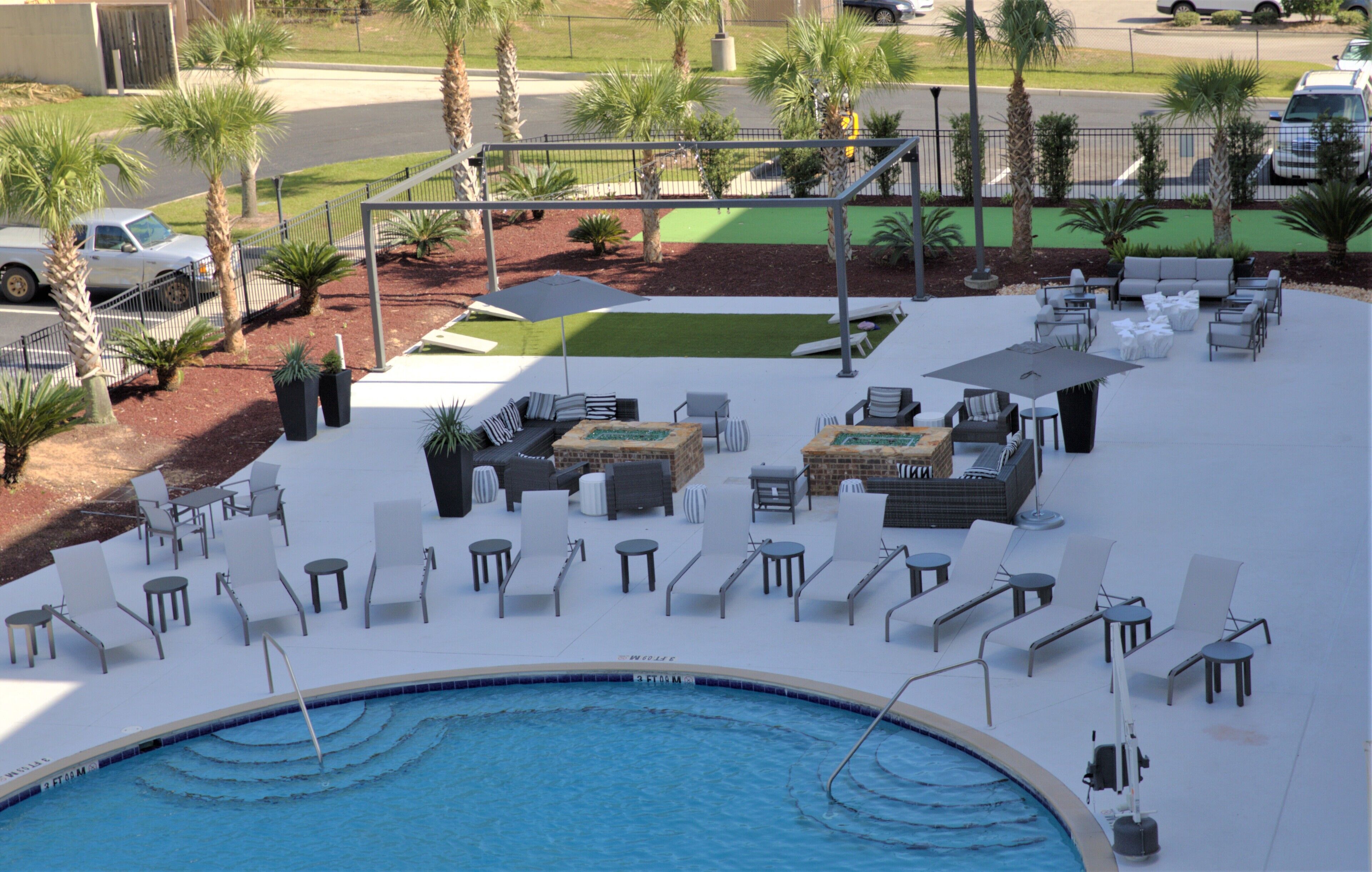 A poolside area with lounge chairs, a small pool, and palm trees.