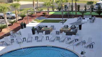 A poolside area with lounge chairs, a small pool, and palm trees.
