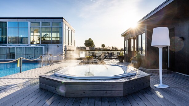 A modern outdoor pool area with a hot tub, lounge chairs, and a wooden deck. - Torekov Hotell (Torekov)