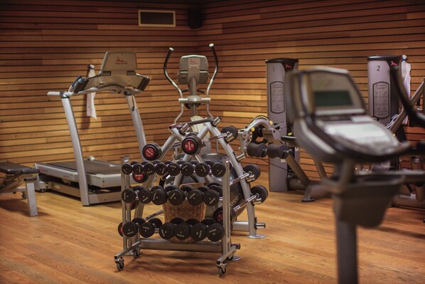 Une salle de sport équipée de matériel d’exercice, notamment des tapis de course, des haltères et des appareils de musculation.