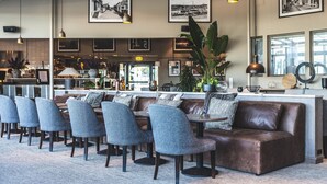 A modern bar area with seating, bar counter, and large windows. - Torekov Hotell (Torekov)