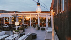An outdoor patio with wicker furniture, potted plants, and a large umbrella. - Torekov Hotell (Torekov)