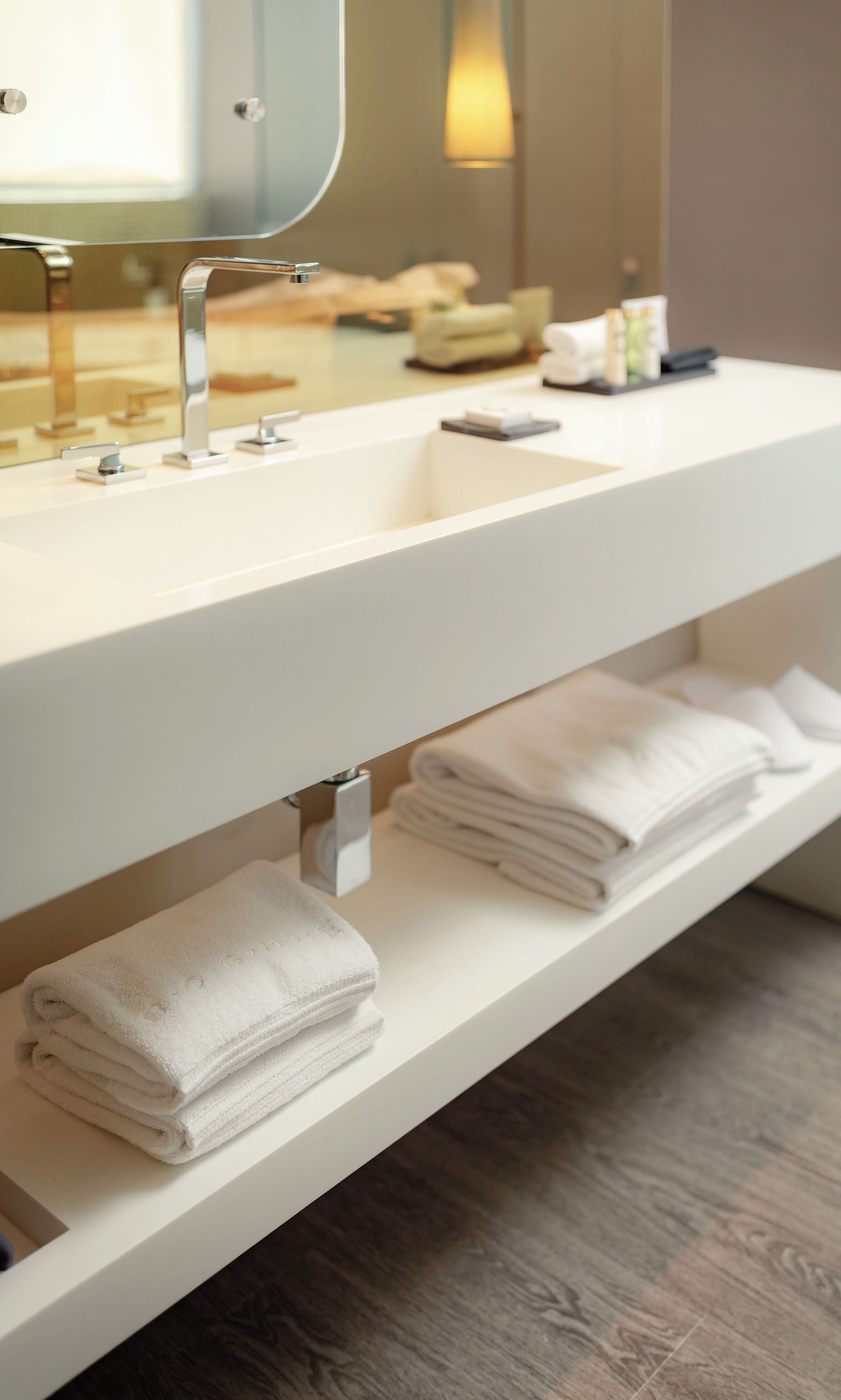 A bathroom with a white sink, a mirror, and a towel rack with folded towels.