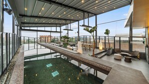 A rooftop infinity pool with a glass barrier, outdoor seating, and a view of the cityscape. - BOG Hotel  (Bogotá)